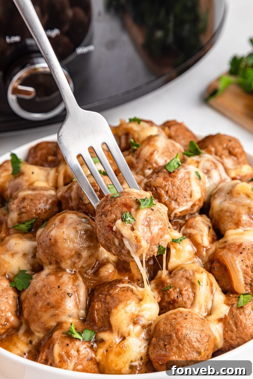 Crock Pot French Onion Meatballs in a bowl with a fork poked into one 