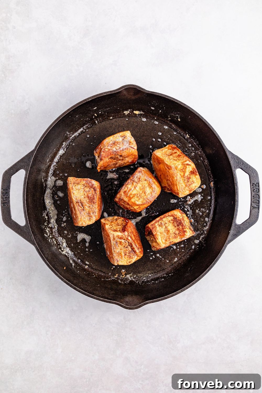 searing Hawaiian Roll French Toast in a cast iron skillet