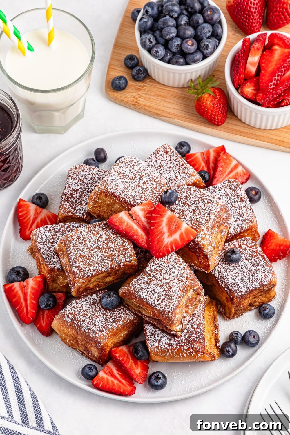 Hawaiian Roll French Toast pieces on a plate with fruit around it 