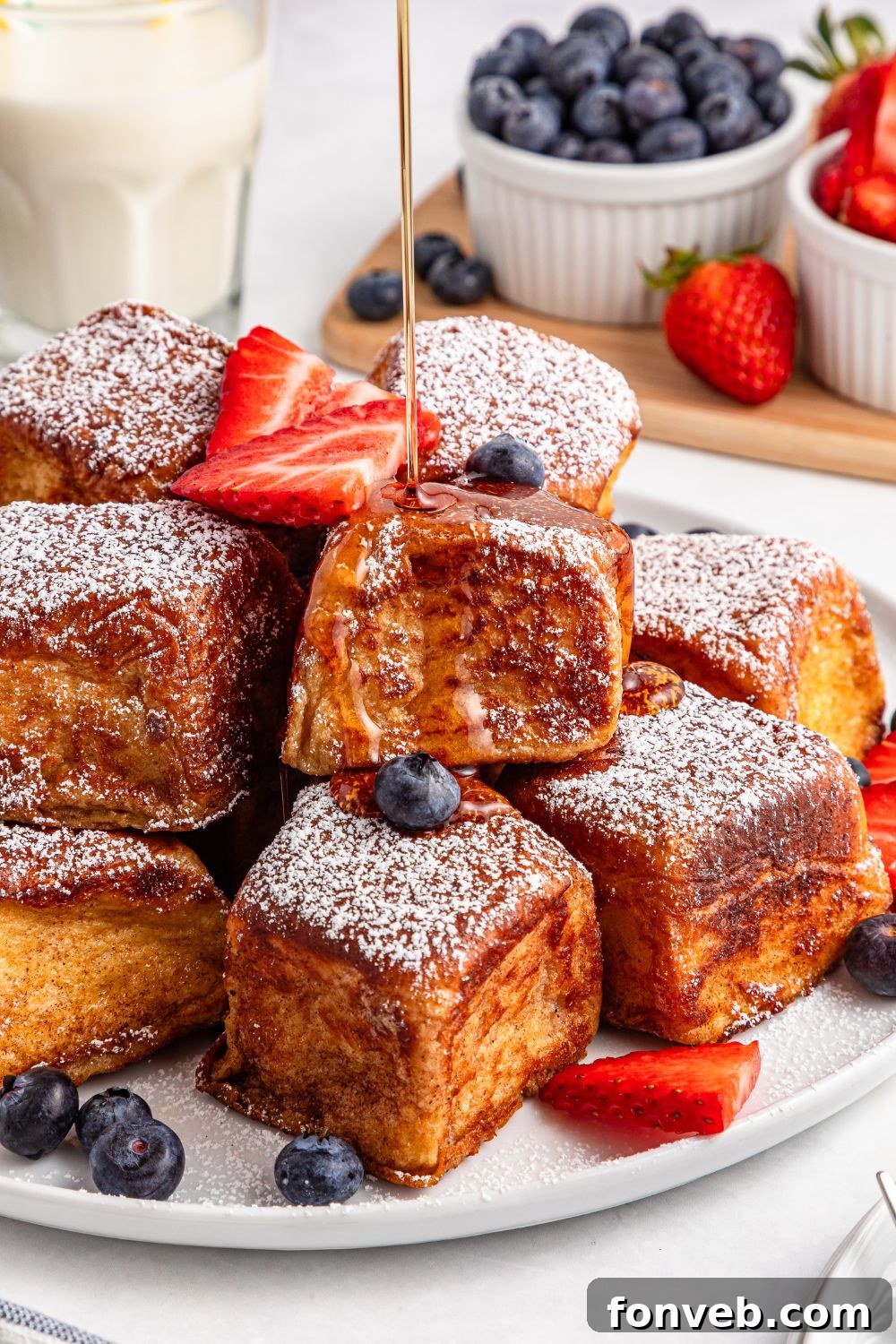 Hawaiian Roll French Toast getting syrup drizzled on top of it on a platter on table 