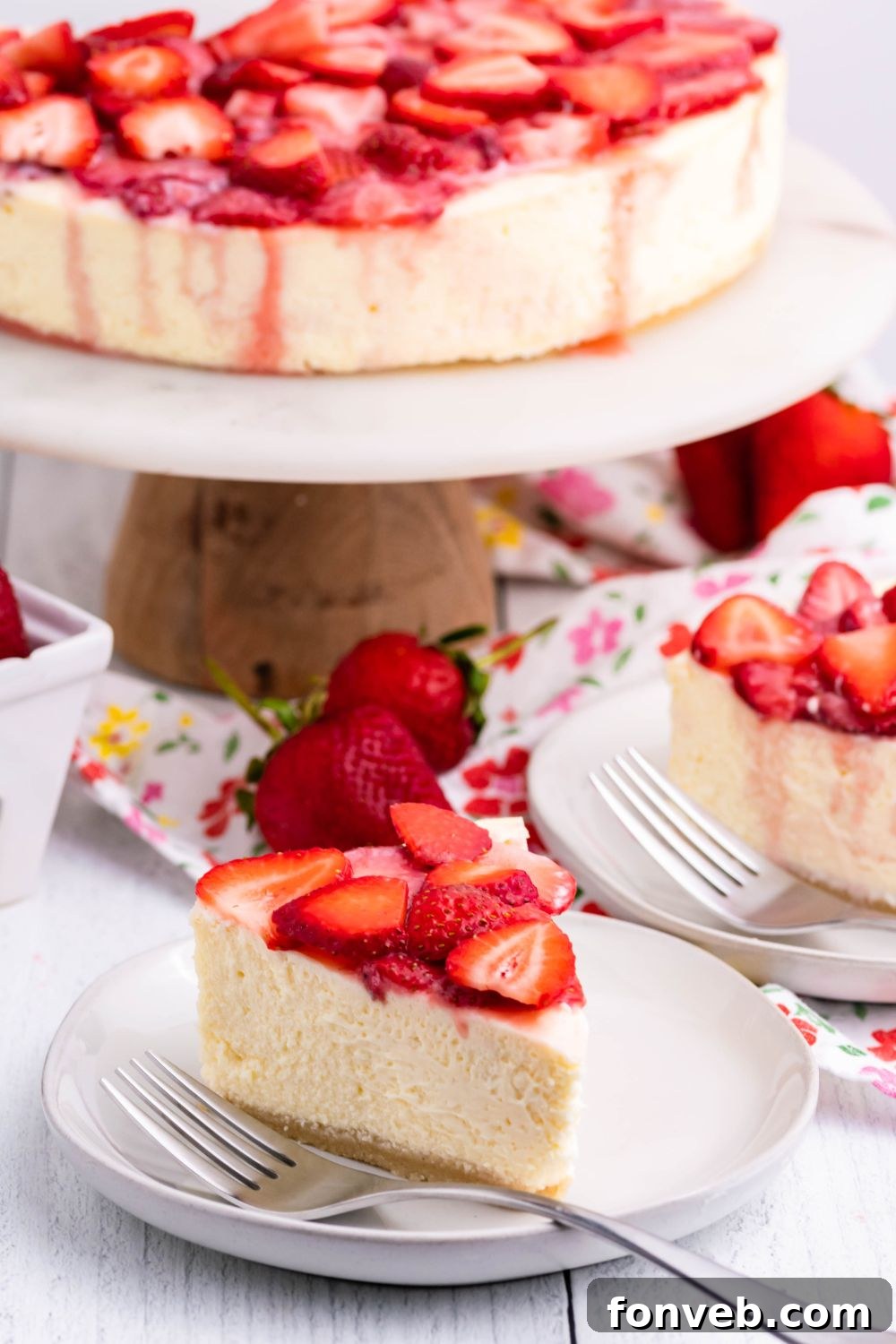 Keto Cheesecake on a pie platter and slices of cheesecake on small plates with berries on top 