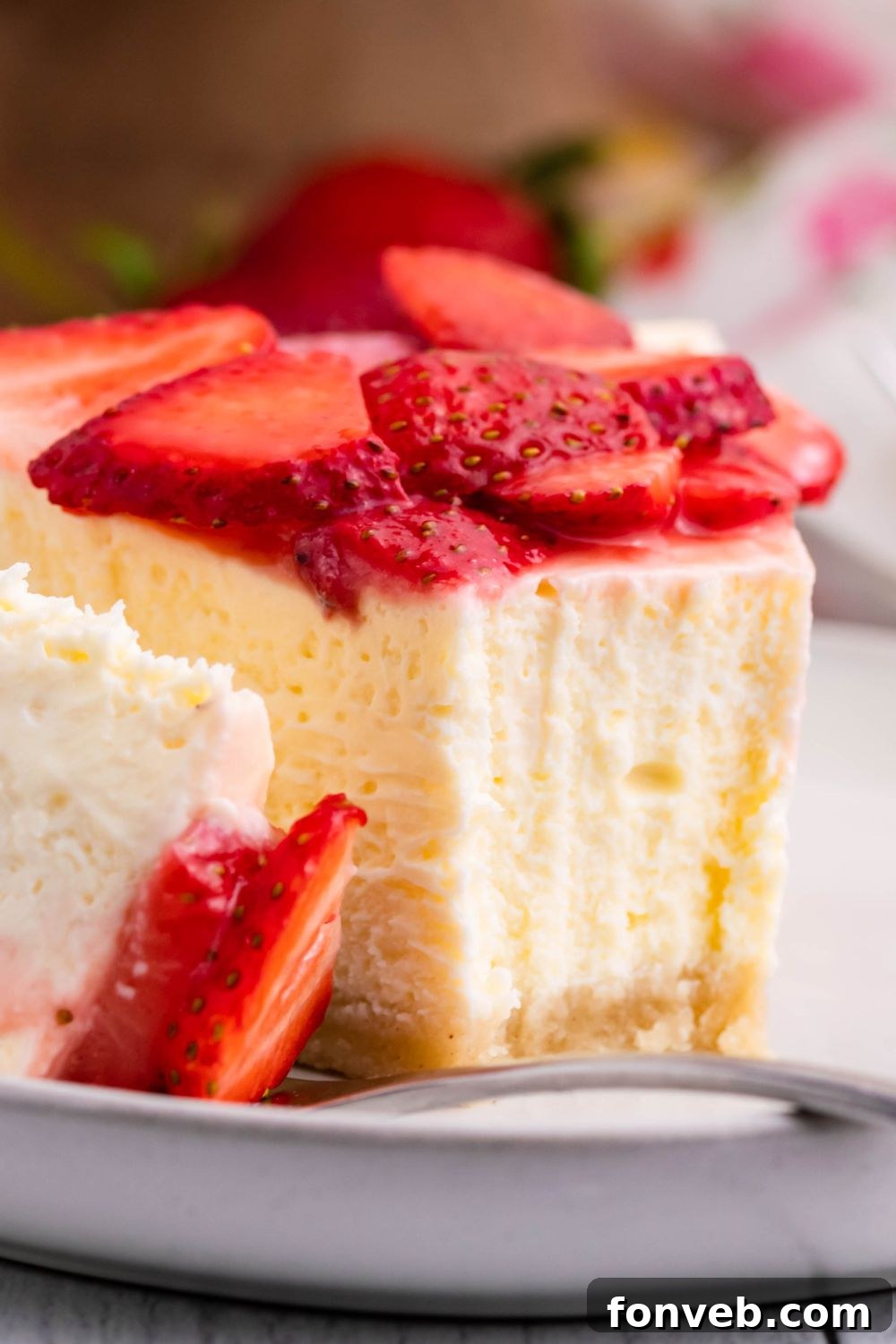 Slice of Keto Cheesecake on a plate with a bite being placed on fork to show the dense texture of cheesecake 