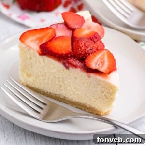 slice of keto cheesecake on a plate topped with strawberries and fork on the side of plate