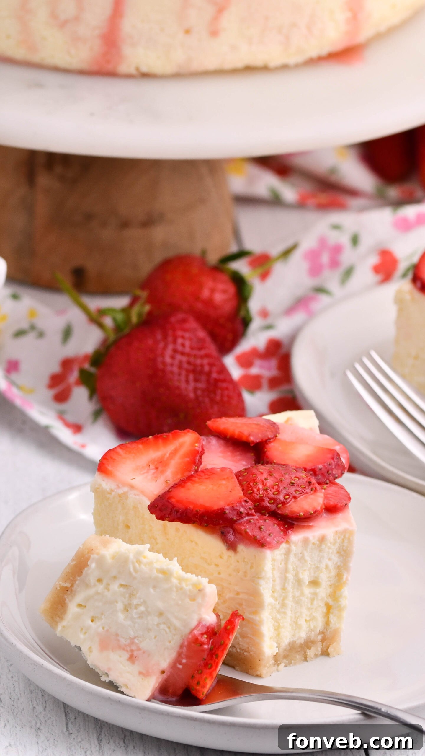 slice of keto cheesecake on a plate topped with strawberries and fork on the side of plate 