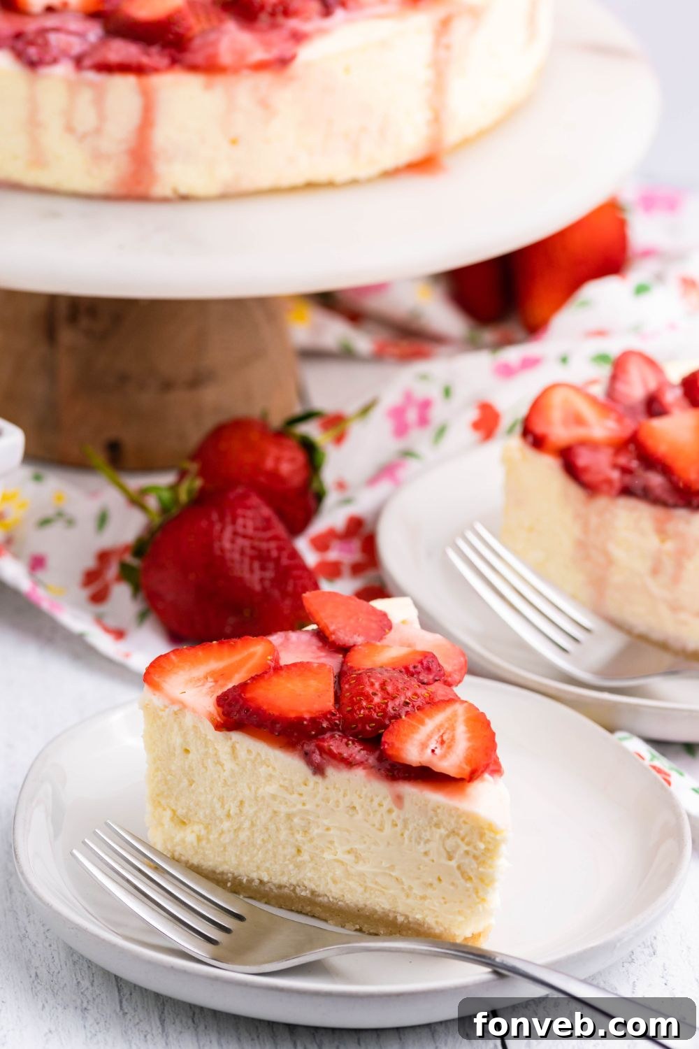 Keto Cheesecake on a platter with slice of cheesecake on the table around it 