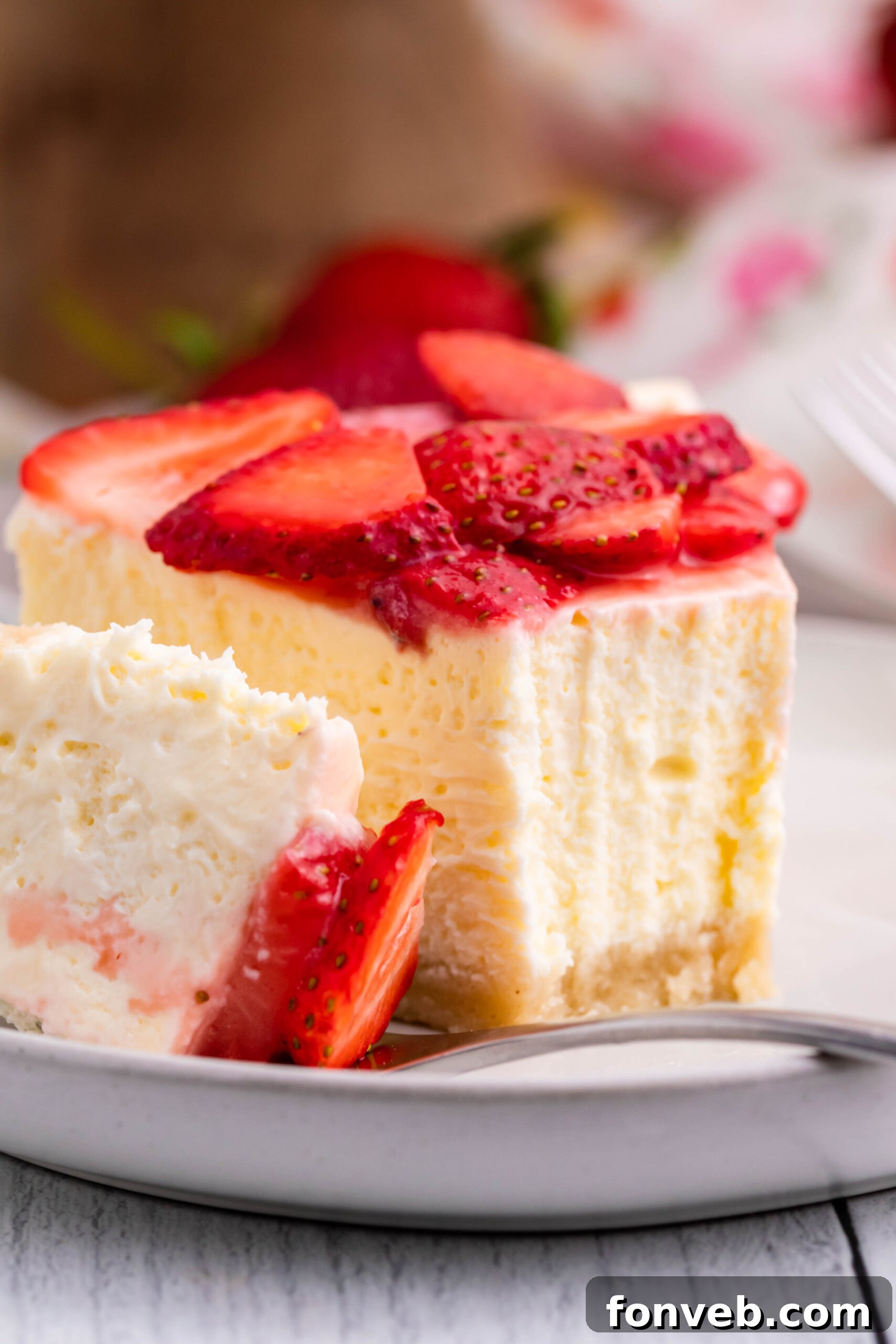 Keto cheesecake on a white plate with strawberries on top
