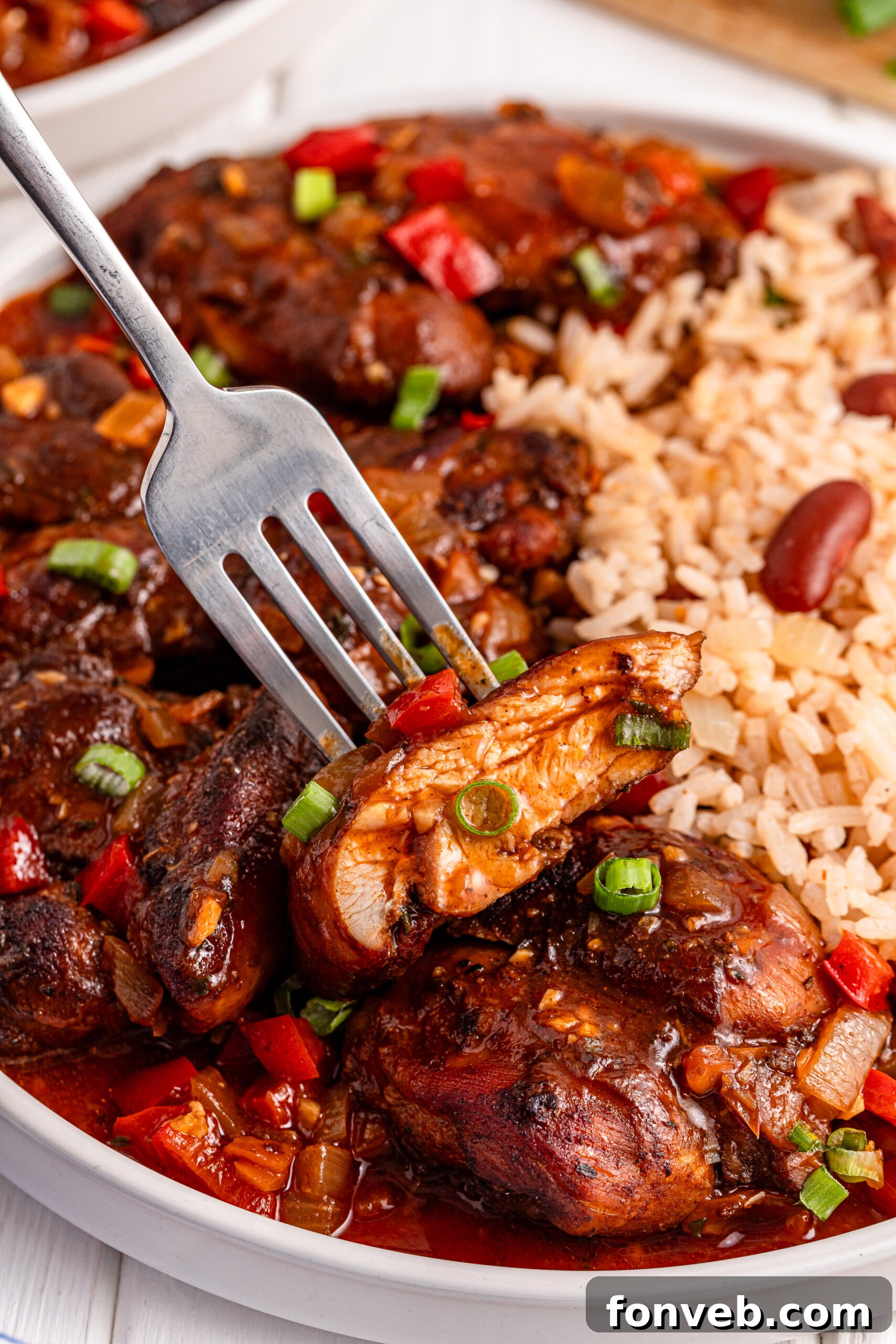 Jamaican Brown Stew Chicken with a bite being lifted up on a fork