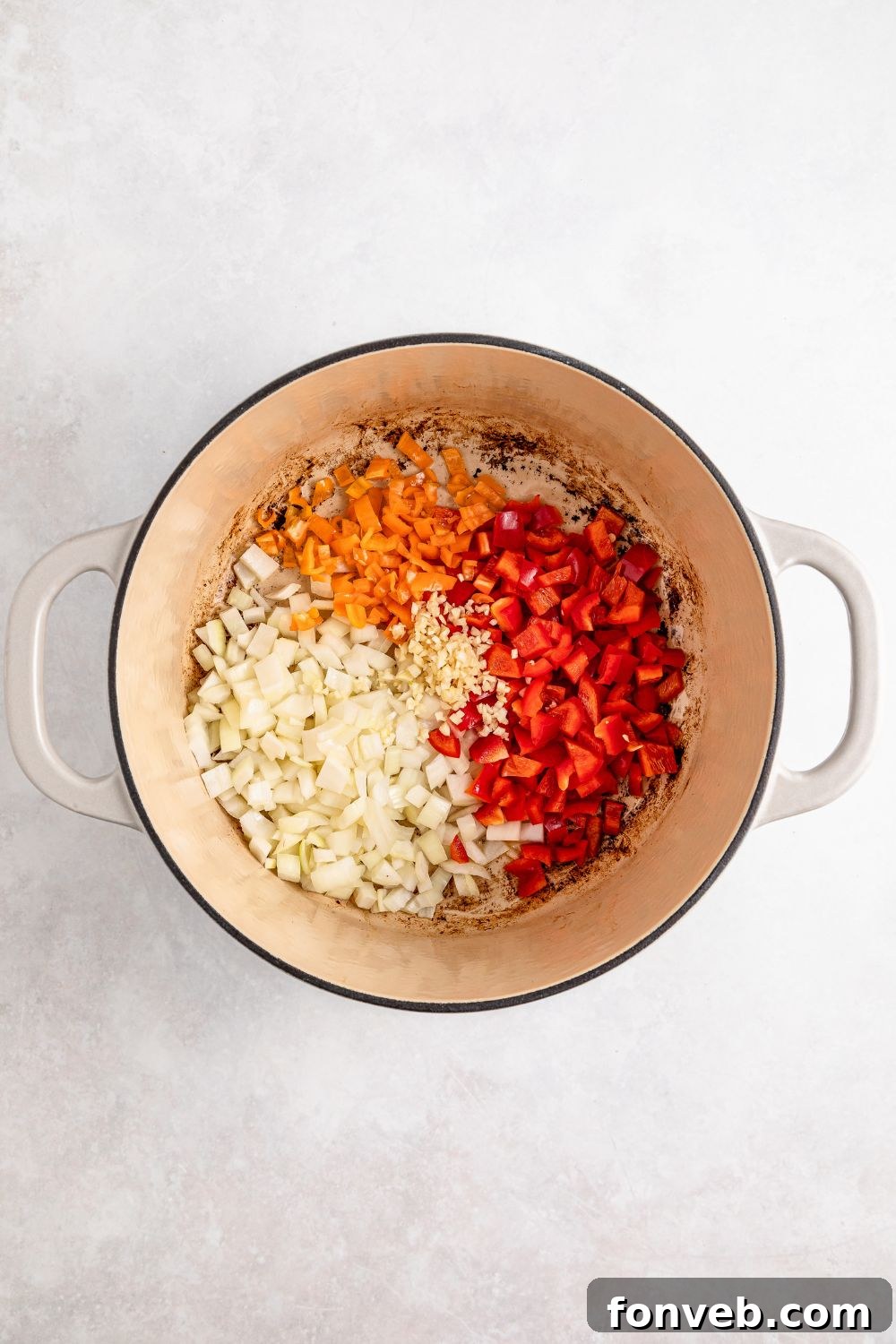 raw diced veggies in a Dutch Oven for Jamaican Brown Stew Chicken
