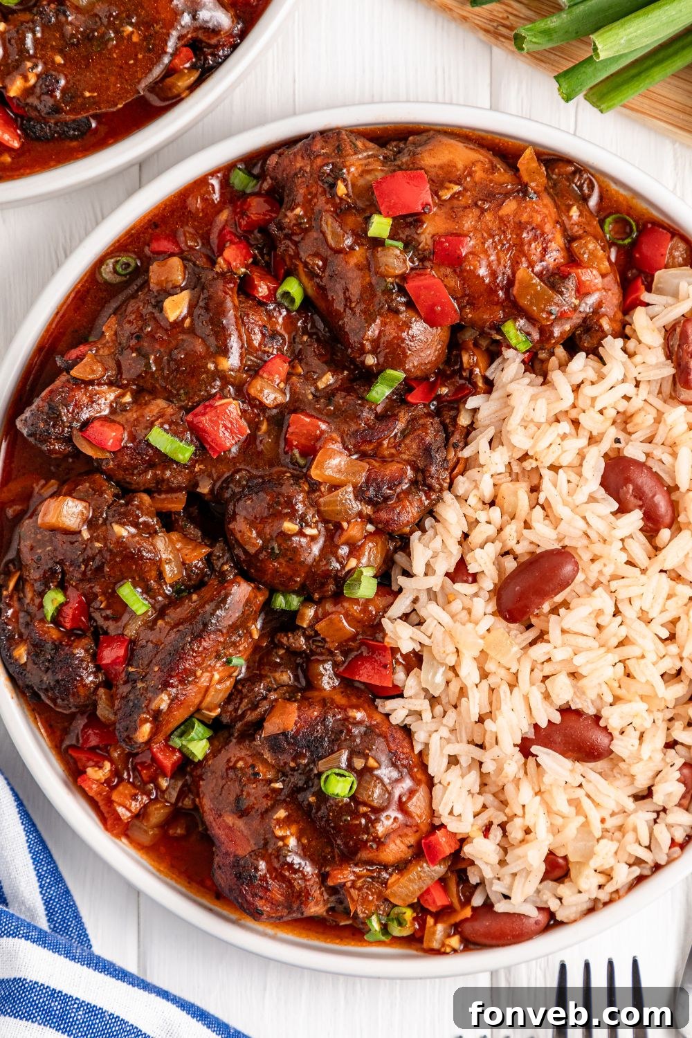 Jamaican Brown Stew Chicken on plate with rice and beans on the side 