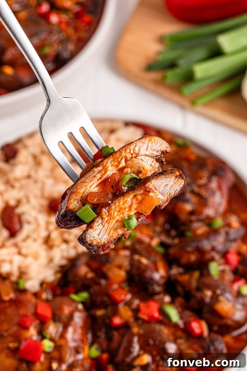 Jamaican Brown Stew Chicken on plate with a fork and a few pieces of chicken on it 