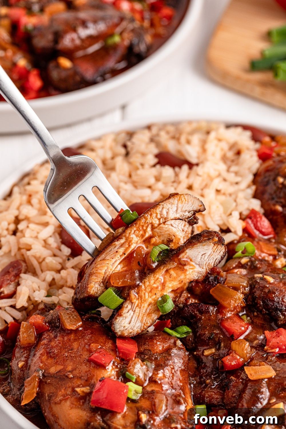 Jamaican Brown Stew Chicken up close showing the texture with a bite being lifted up
