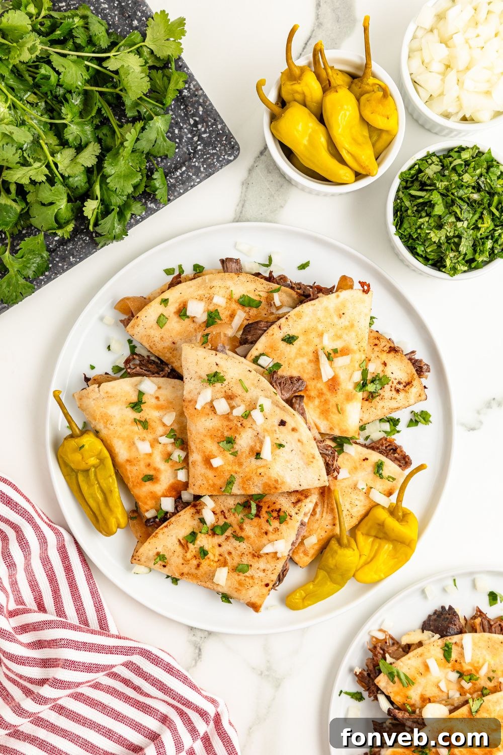 Hearty Mississippi Melt Quesadillas 16 plate with beef quesadillas on them with peppers, onions, and more around the table