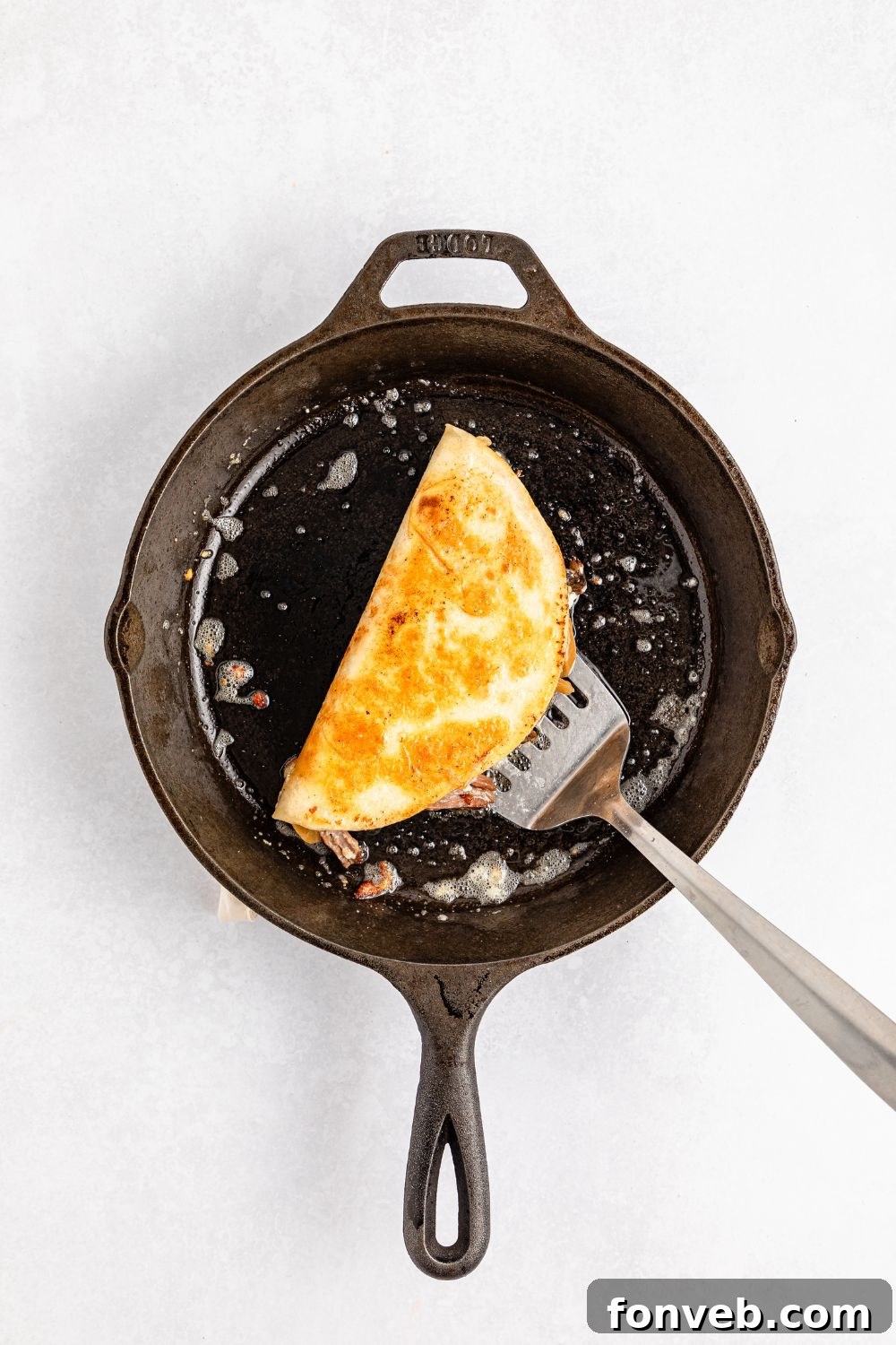 Hearty Mississippi Melt Quesadillas 7 Mississippi Pot Roast Quesadillas in a skillet with a spatula under it