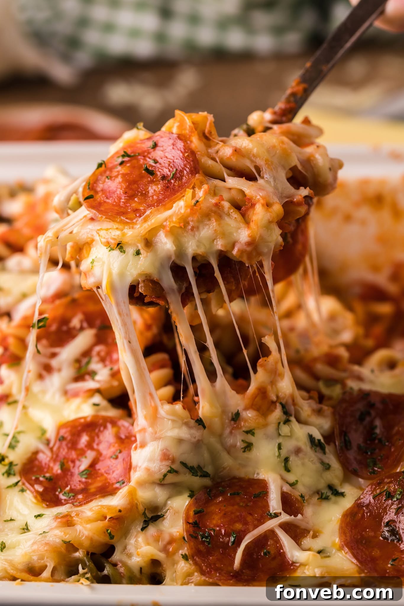 Cheesy TikTok Pizza Pasta Bake 2 Tik Tok Pizza Pasta Casserole with a big cheesy bite being lifted out of the baking dish