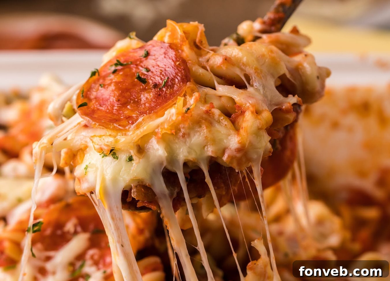 Cheesy TikTok Pizza Pasta Bake 6 Tik Tok Pizza Pasta Casserole being lifted up by a large serving spoon