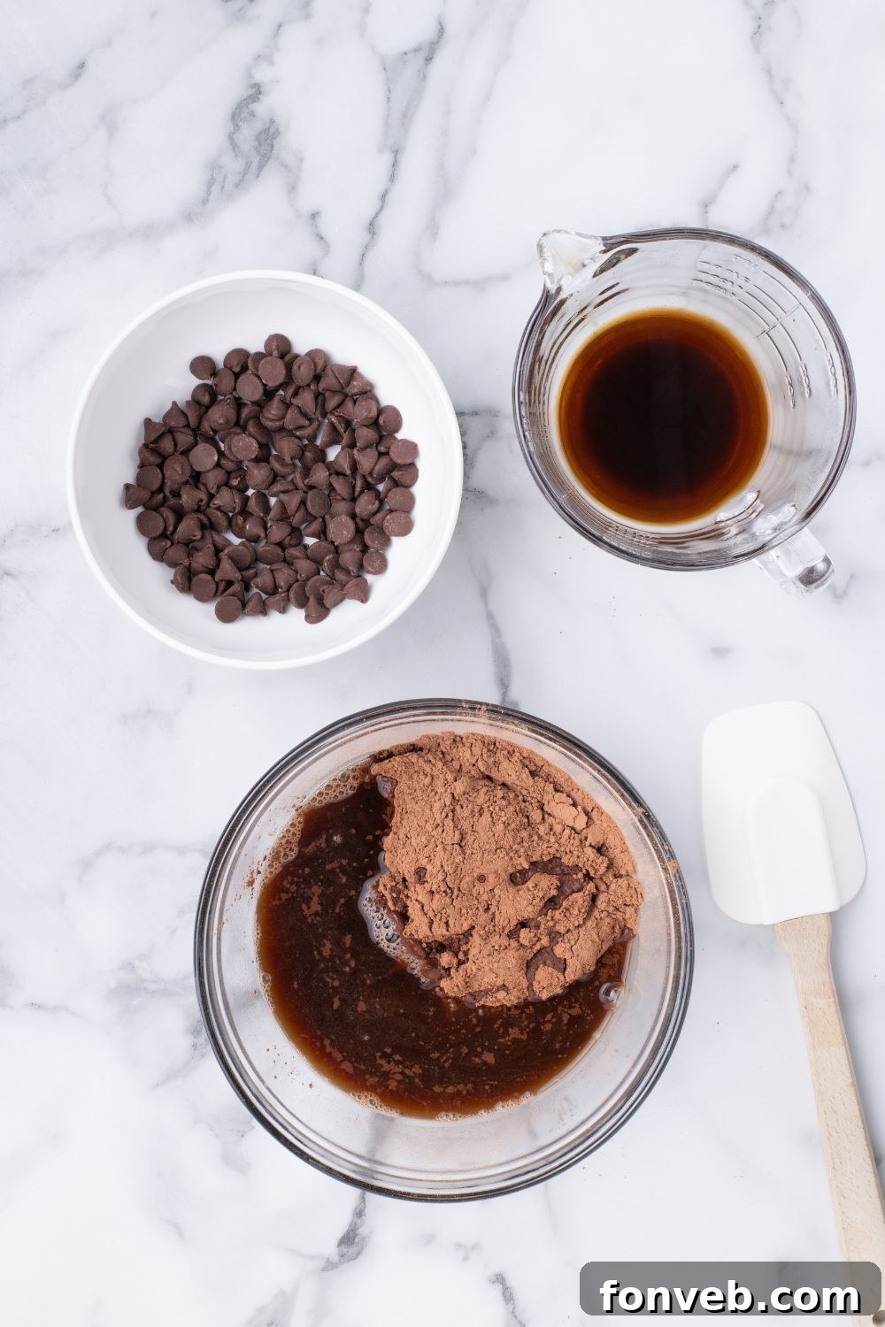 Decadent Chocolate Cream Dream 16 Cake batter in a mixing bowl, accompanied by a small bowl of chocolate chips and a cup of coffee, illustrating the preparation stage.