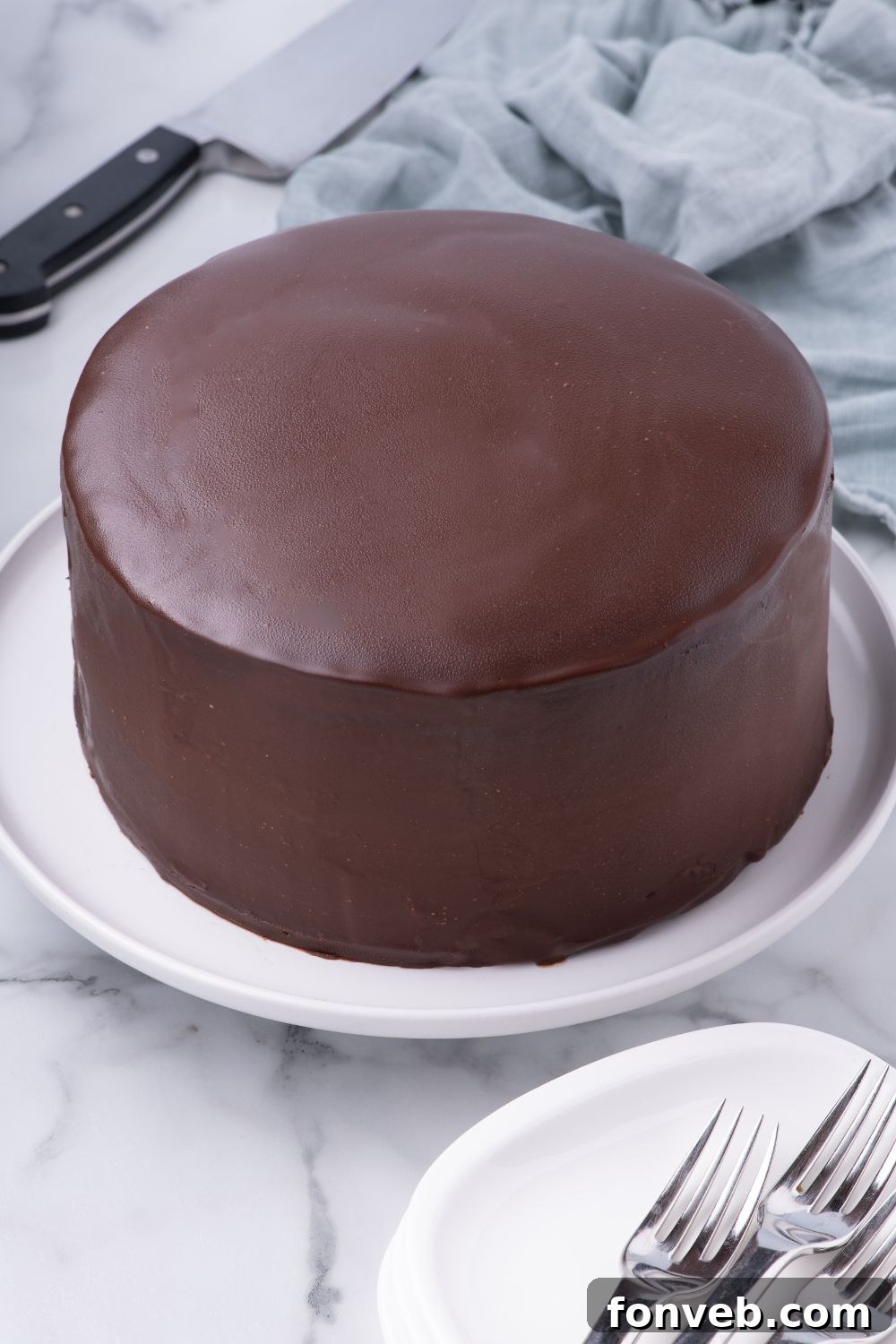 Decadent Chocolate Cream Dream 19 A fully assembled and glazed Ding Dong Cake, exquisitely presented on a plate on a table, ready to be served and enjoyed.