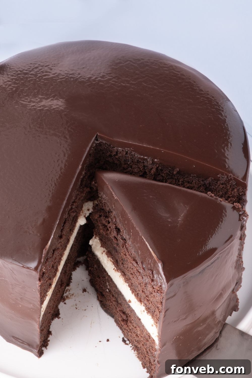 Decadent Chocolate Cream Dream 24 An enticing view of a Ding Dong Cake with a slice being gracefully lifted by a cake spatula, highlighting its rich layers and glossy finish.