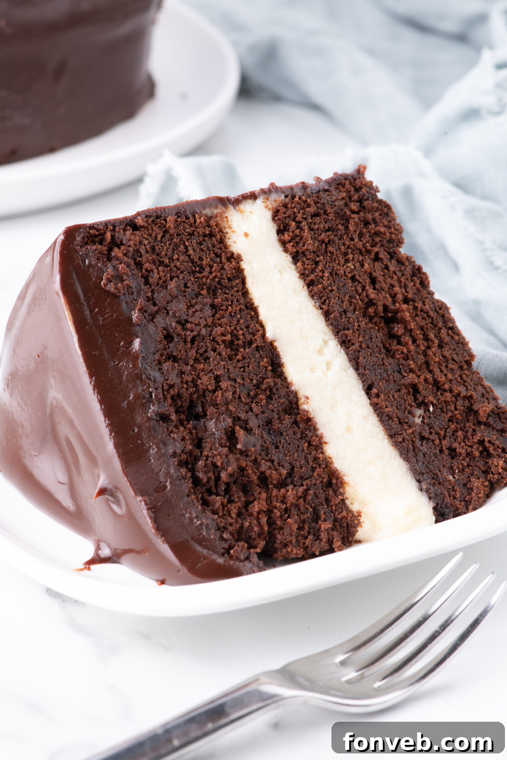 Decadent Chocolate Cream Dream 5 An intimate close-up shot of a slice of Ding Dong Cake on a white plate, revealing the exquisite texture of the chocolate cake and the smooth, pristine white interior of the cream filling.