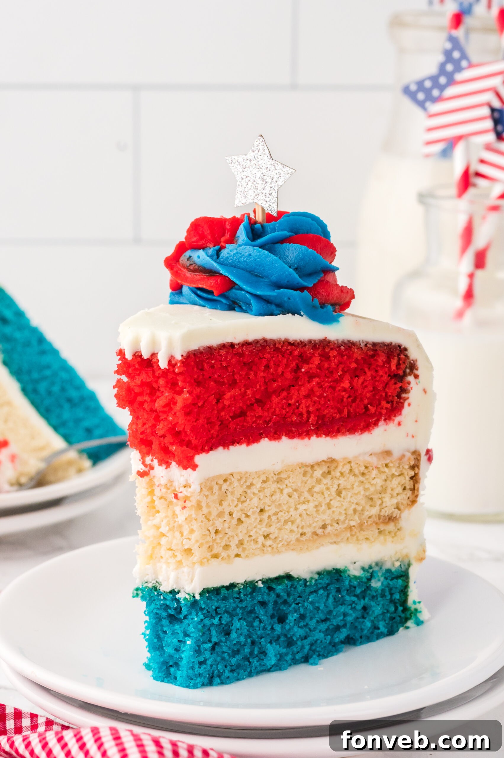 Slice of American Flag Layered Cake on a white plate with cups of milk behind the cake
