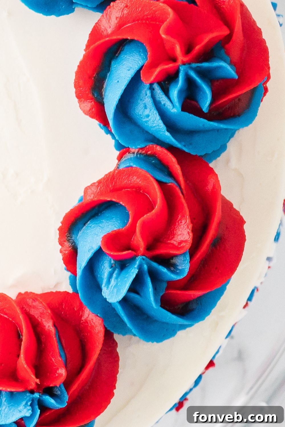 red and blue swirls of frosting piped on top of a cake 