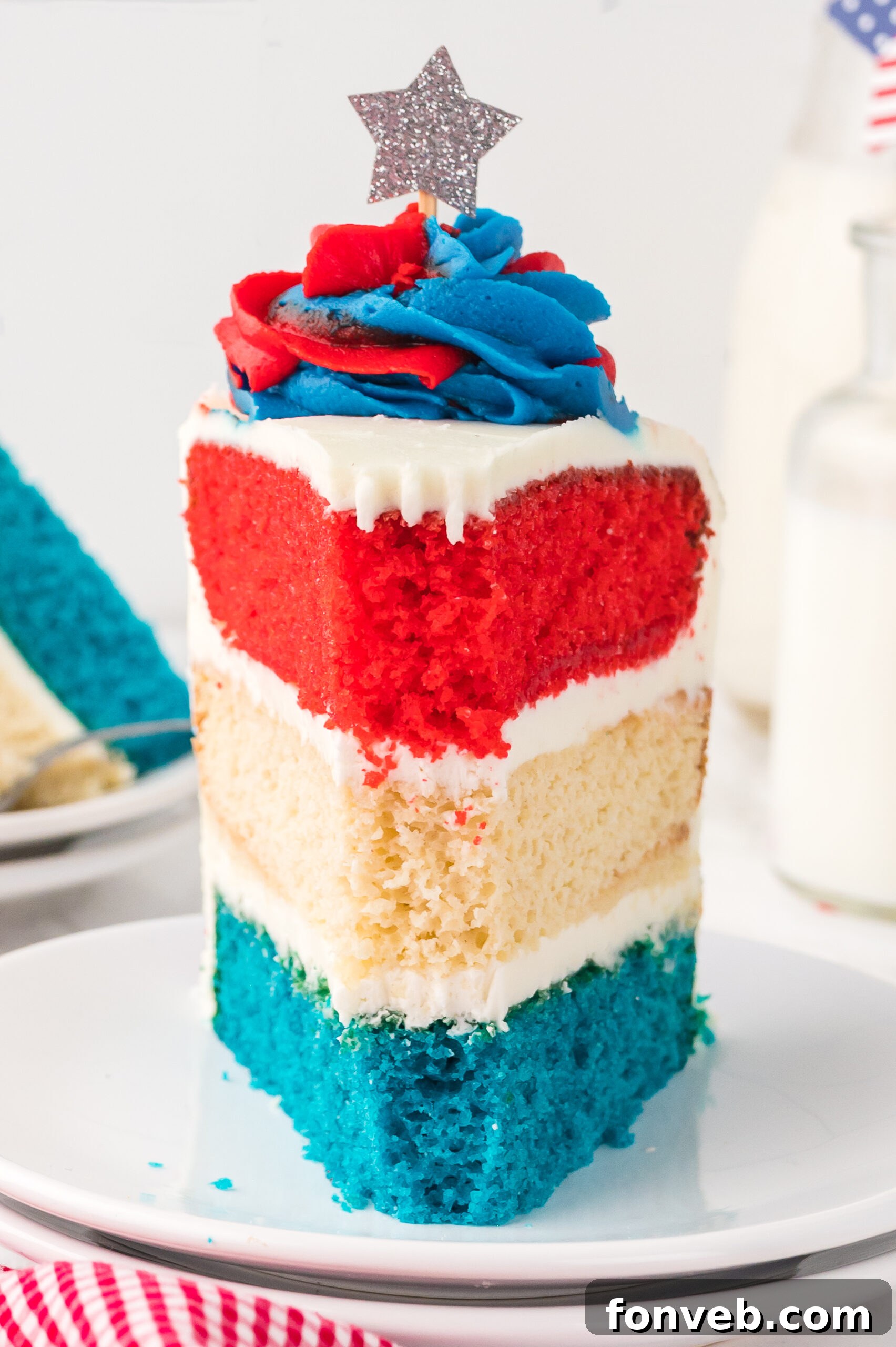 front view of a Slice of American Flag Layered Cake on a white plate with a bite missing