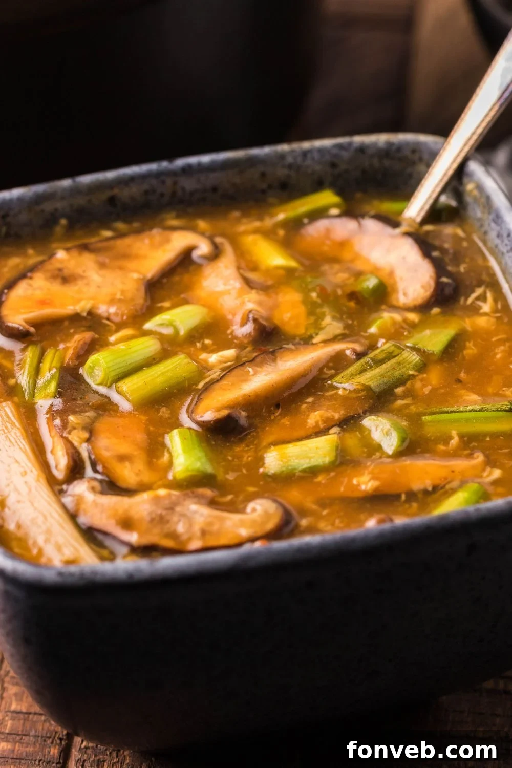 PF Chang's Fiery & Tangy Soup 14 PF Changs Hot And Sour Soup in a square bowl with a spoon in bowl on table