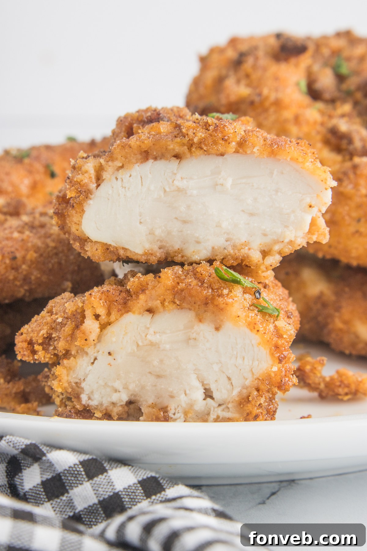 Ultra Crispy Air Fryer Chicken Tenders 11 A cooked Air Fryer Chicken Tender cut open on a white plate, revealing its perfectly juicy and tender interior