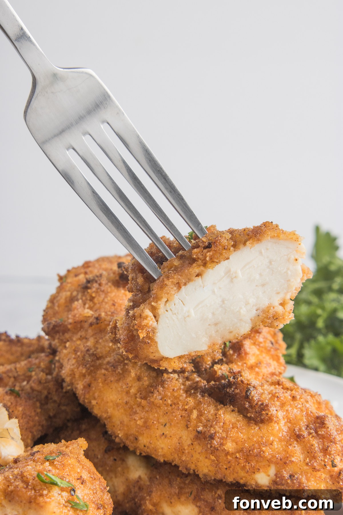 Ultra Crispy Air Fryer Chicken Tenders 12 A fork lifting up a delicious bite of a crispy Air Fryer Chicken Tender, showing its golden exterior