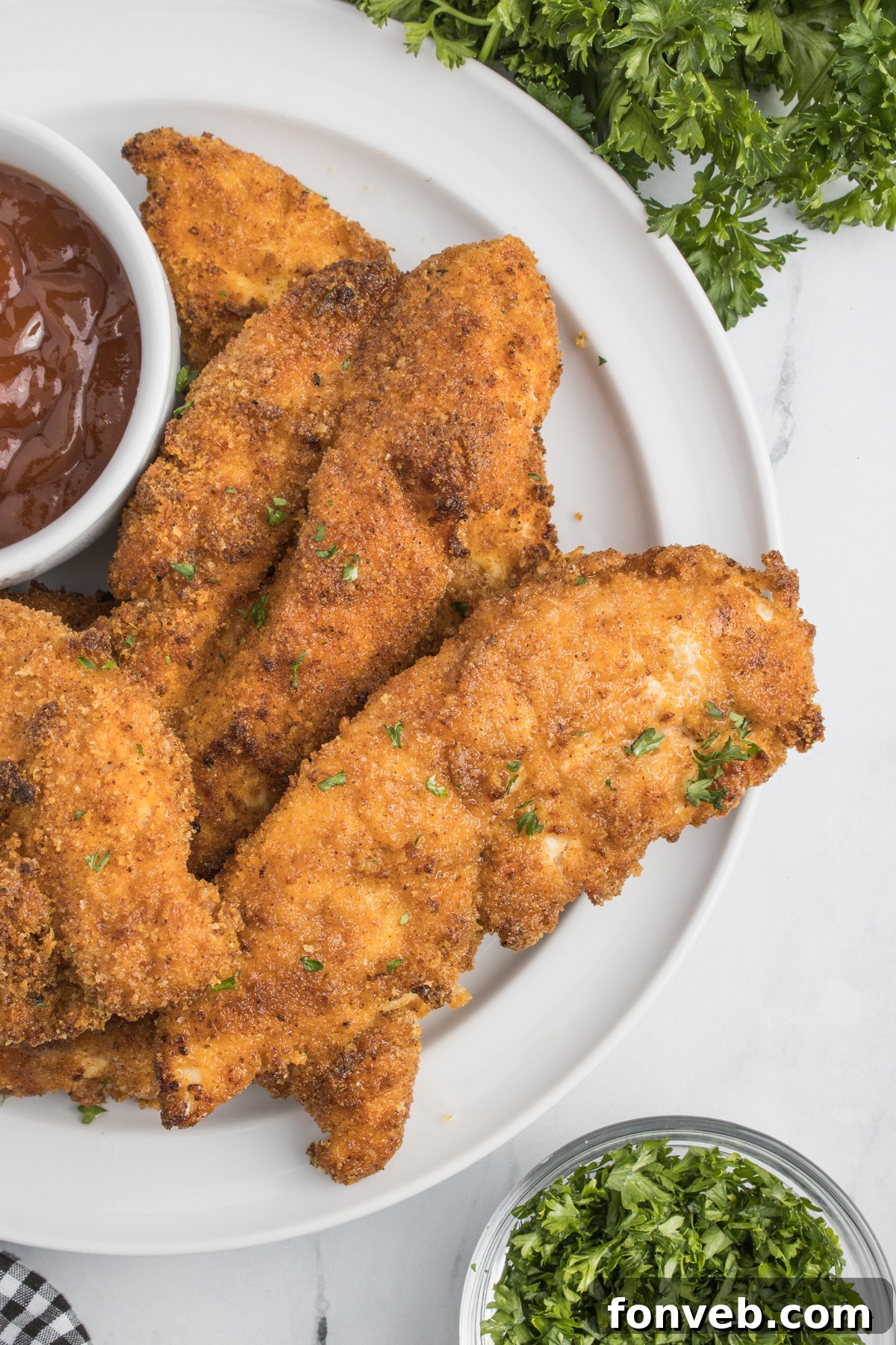 Ultra Crispy Air Fryer Chicken Tenders 14 A beautifully arranged plate of Air Fryer Chicken Tenders, served with a small cup of BBQ sauce for dipping