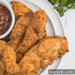 Ultra Crispy Air Fryer Chicken Tenders 15 Air Fryer Chicken Tenders on a white plate with a small cup of BBQ sauce on the side