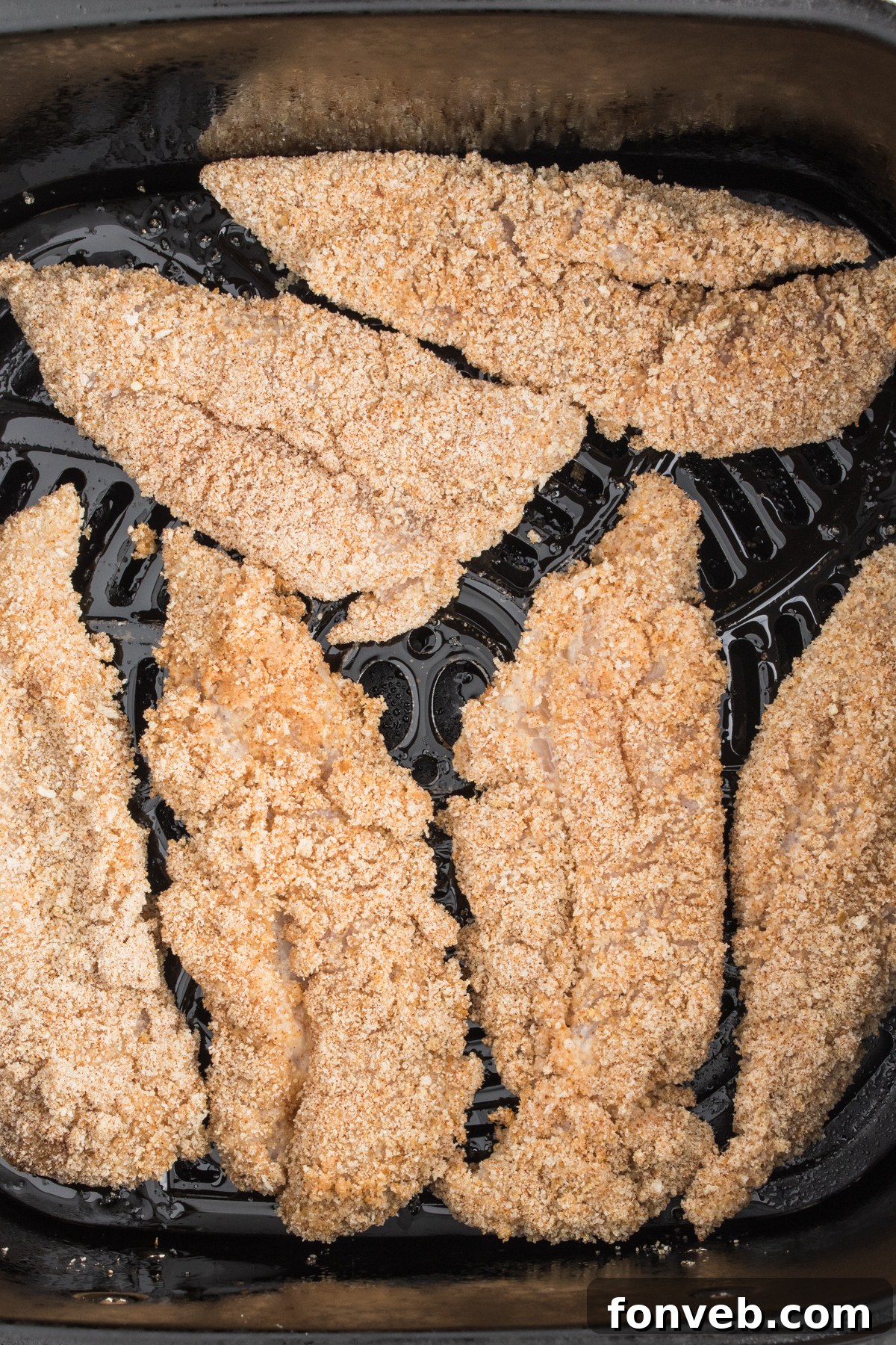 Ultra Crispy Air Fryer Chicken Tenders 8 Uncooked Air Fryer Chicken Tenders neatly arranged in a single layer inside the air fryer basket, ready for cooking