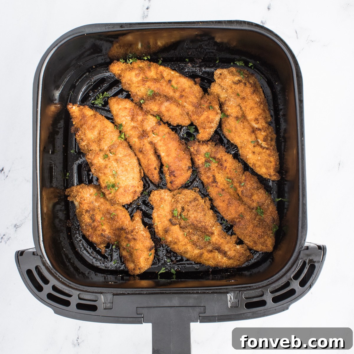 Ultra Crispy Air Fryer Chicken Tenders 9 Perfectly cooked Air Fryer Chicken Tenders resting in the air fryer basket, golden brown and crispy