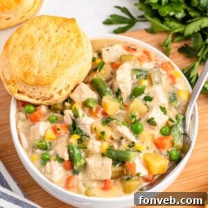 Slow Cooker Chicken Pot Pie in a bowl with a biscuit on side of bowl