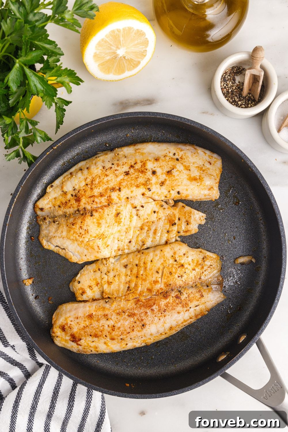 Golden Pan-Seared Tilapia 8 cooked Pan Fried Tilapia in a skillet on table