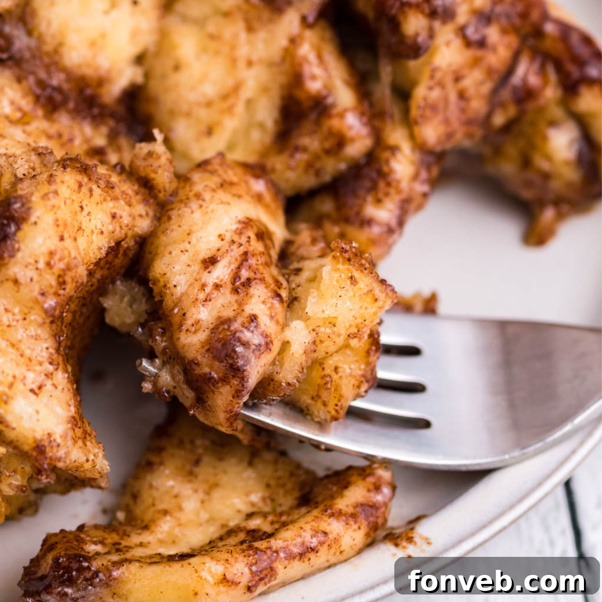 Up close shot of a piece of cinnamon roll casserole on a silver fork. 