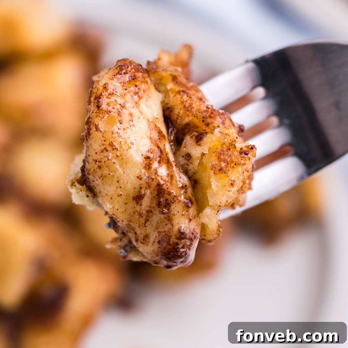 Up close shot of a piece of Cinnamon Roll Casserole on a silver fork. 