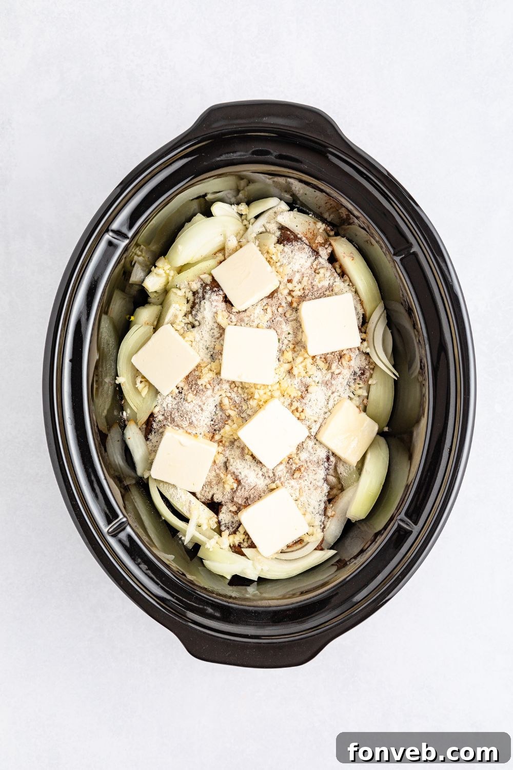 Ultimate Mississippi Pot Roast Sandwiches 11 Seasonings and butter on top of pot roast in a slow cooker