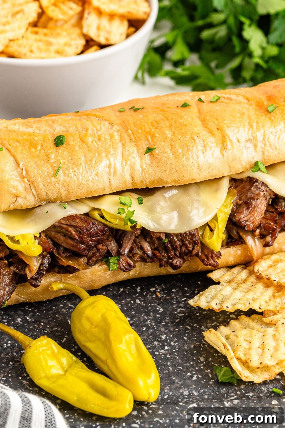 Ultimate Mississippi Pot Roast Sandwiches 16 Mississippi Pot Roast Sandwich on table with some chips and peppers in front of sandwich