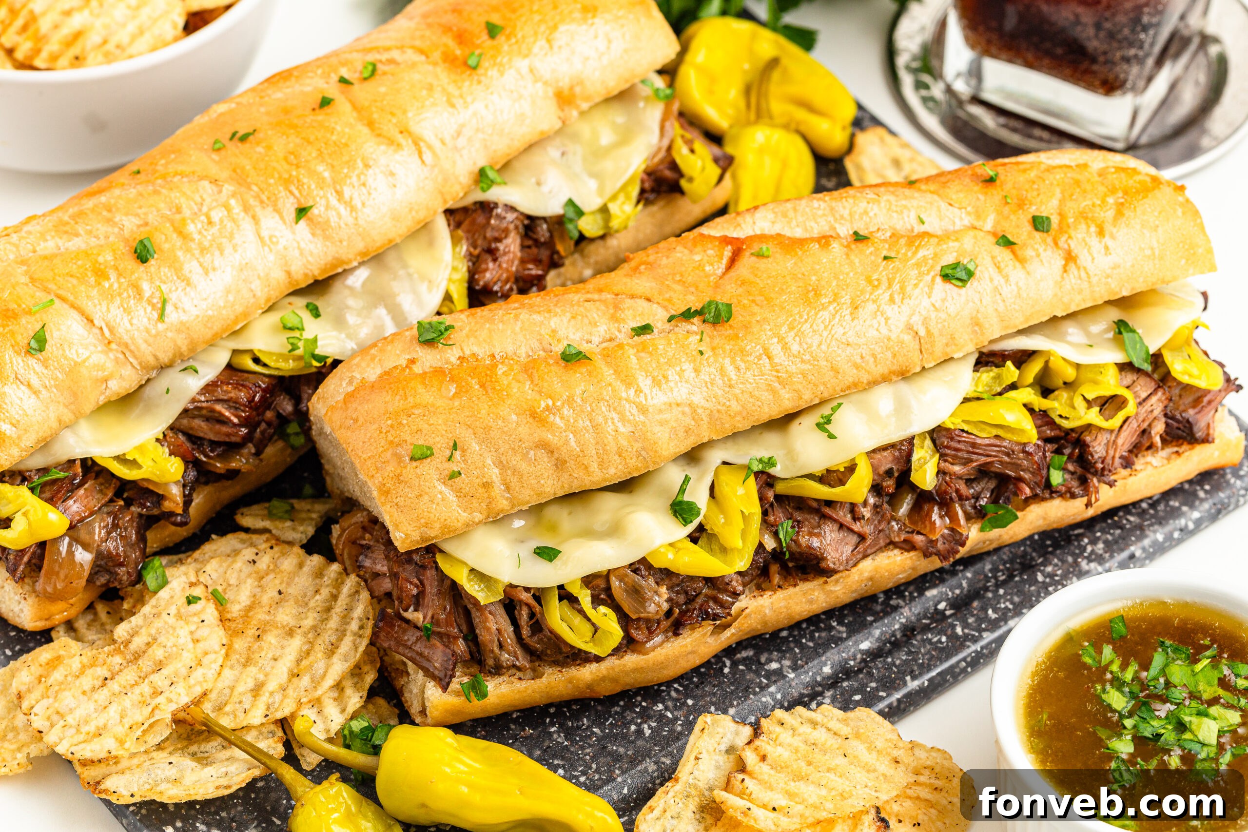 Ultimate Mississippi Pot Roast Sandwiches 3 Two Mississippi Pot Roast Sandwiches on a cutting board with chips on the side