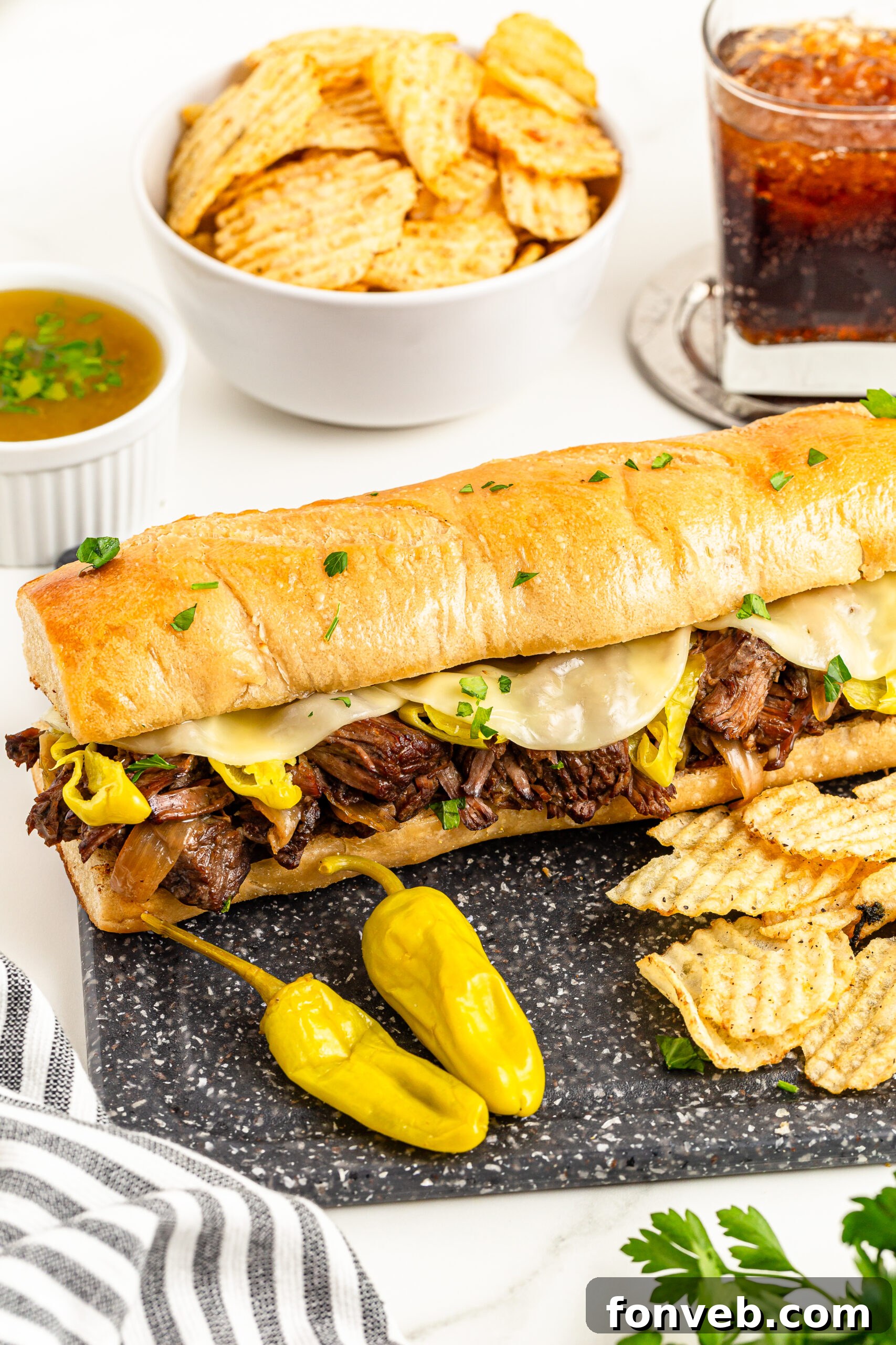 Ultimate Mississippi Pot Roast Sandwiches 4 One Mississippi Pot Roast Sandwich on a cutting board with chips on the side and a soda