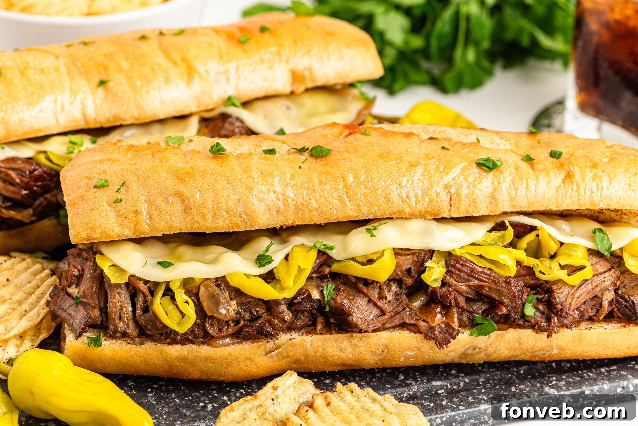 Ultimate Mississippi Pot Roast Sandwiches 5 Side view of Two Mississippi Pot Roast Sandwiches on a cutting board with chips on the side