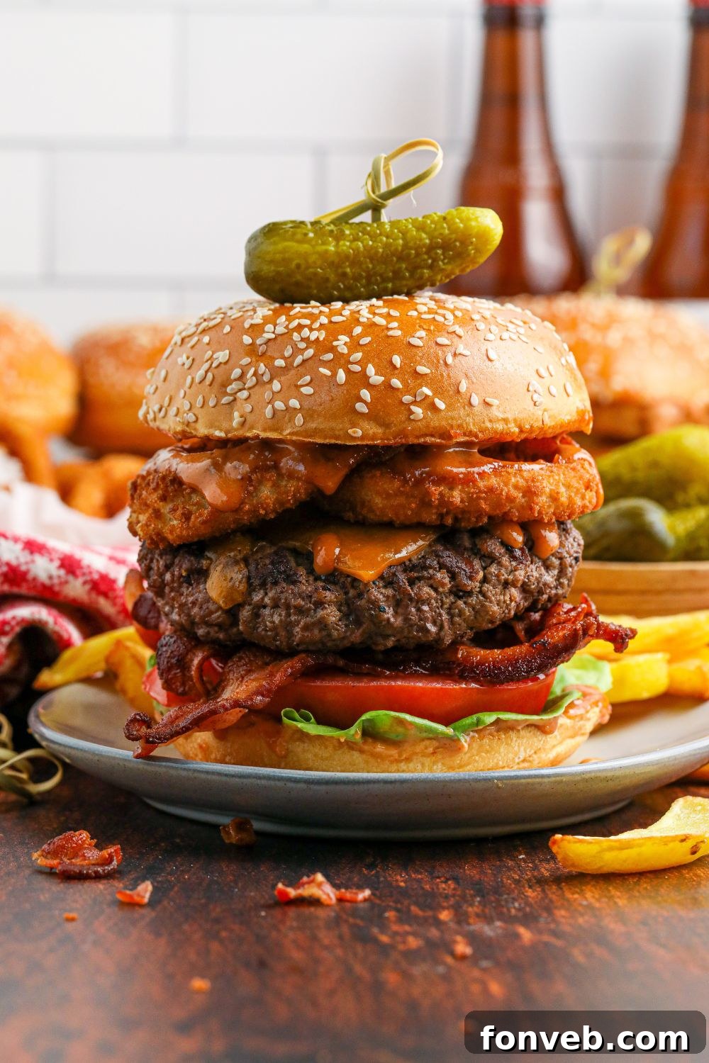 Chuck Wagon Burger 16 A Cowboy Burger presented on a plate with a pickle and a toothpick securing the bun, highlighting its perfect stack.