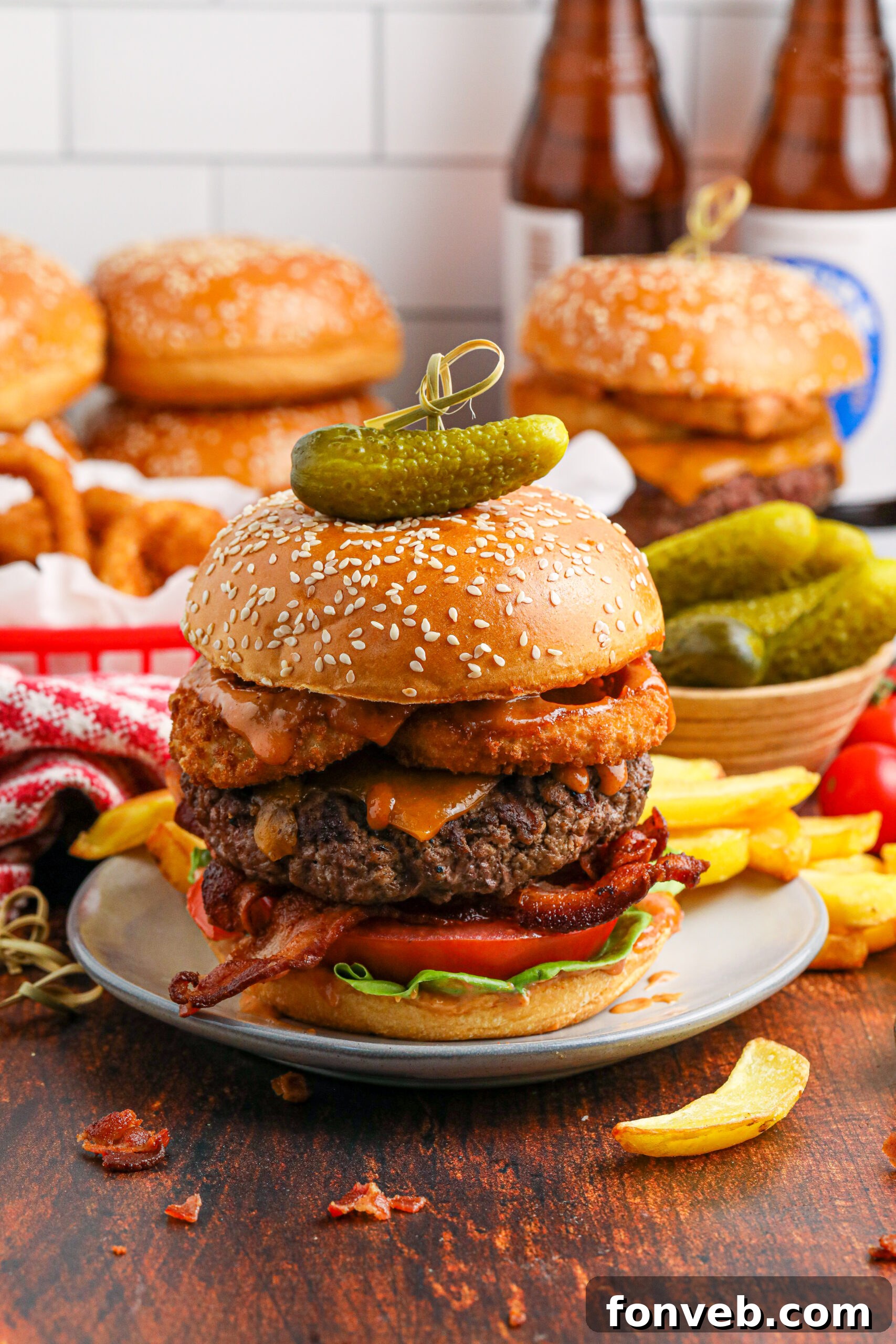 Chuck Wagon Burger 6 A wider shot of a Cowboy Burger on a white plate, accompanied by a bowl of pickles and a serving of fries, ready to be enjoyed.