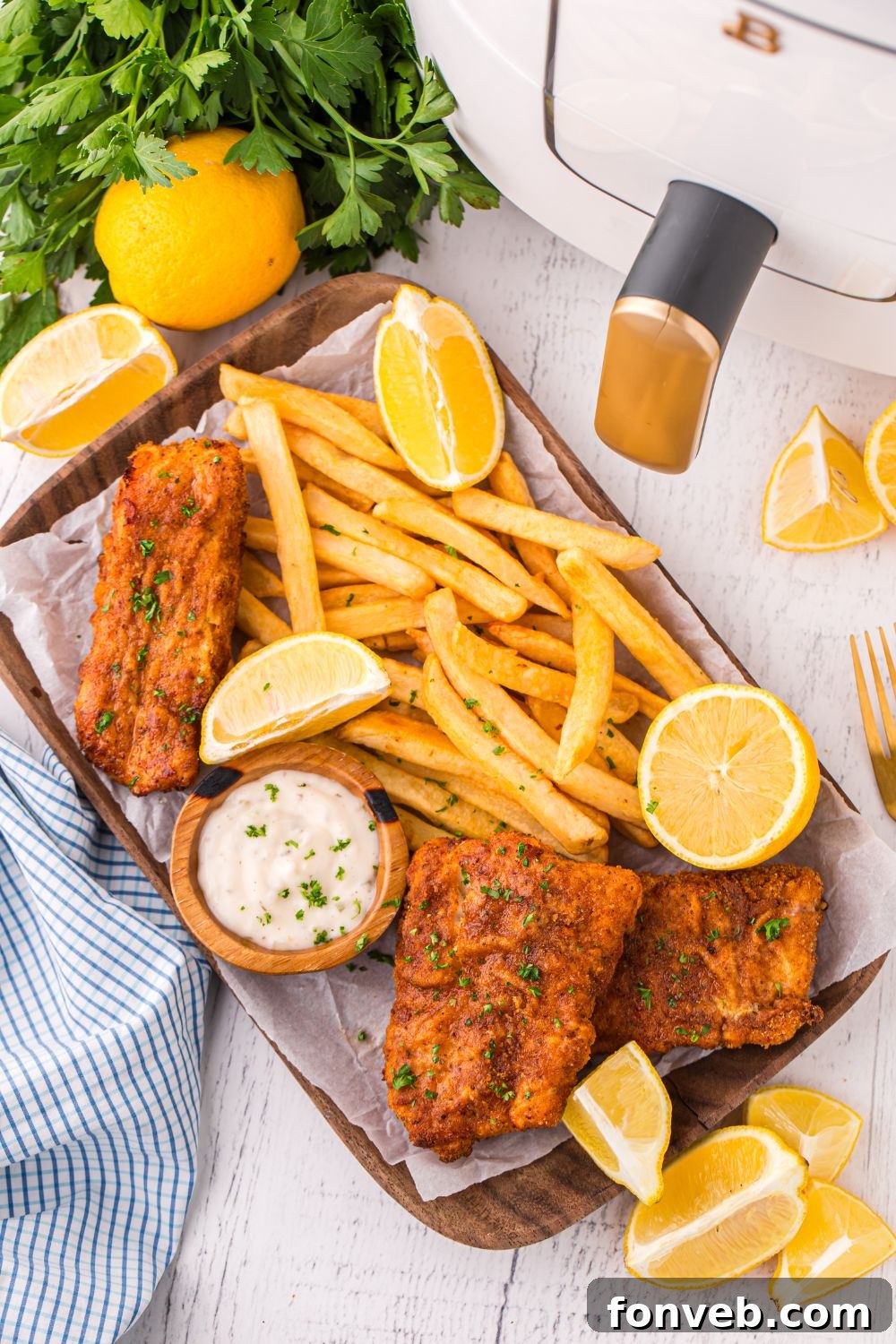 Crispy Air-Fried Fish and Chips 17 overhead look of Air Fryer Fish And Chips on a tray on table with lemons, parsley, and air fryer to side