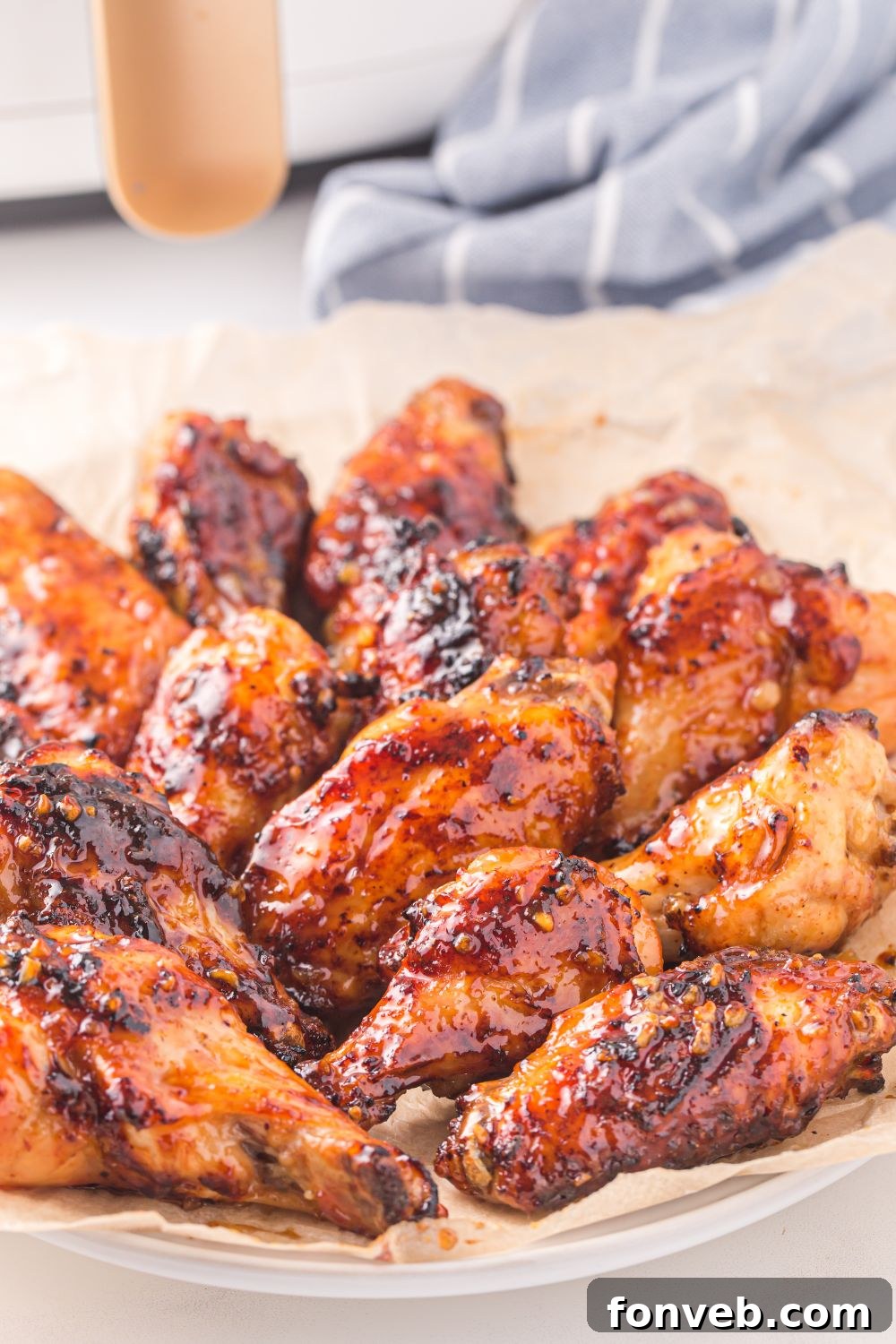 Air Fryer Honey Chicken Wings on a plate with a blue striped towel in background 