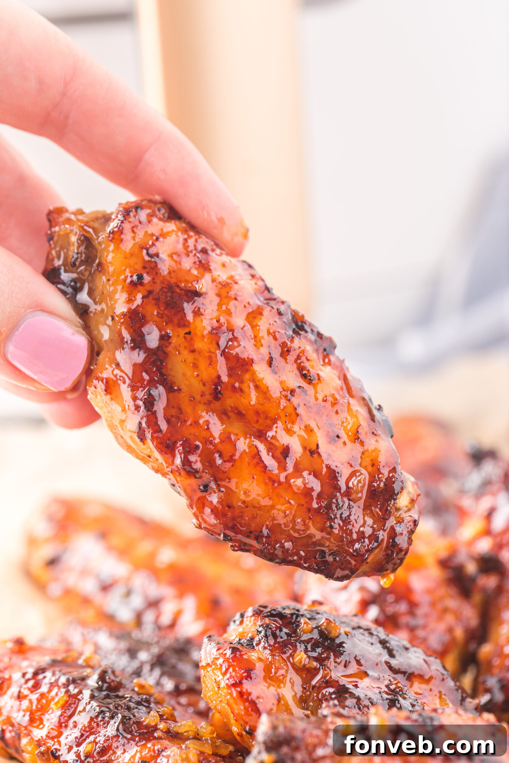 Hand holding up one Air Fryer Honey Garlic Chicken Wing