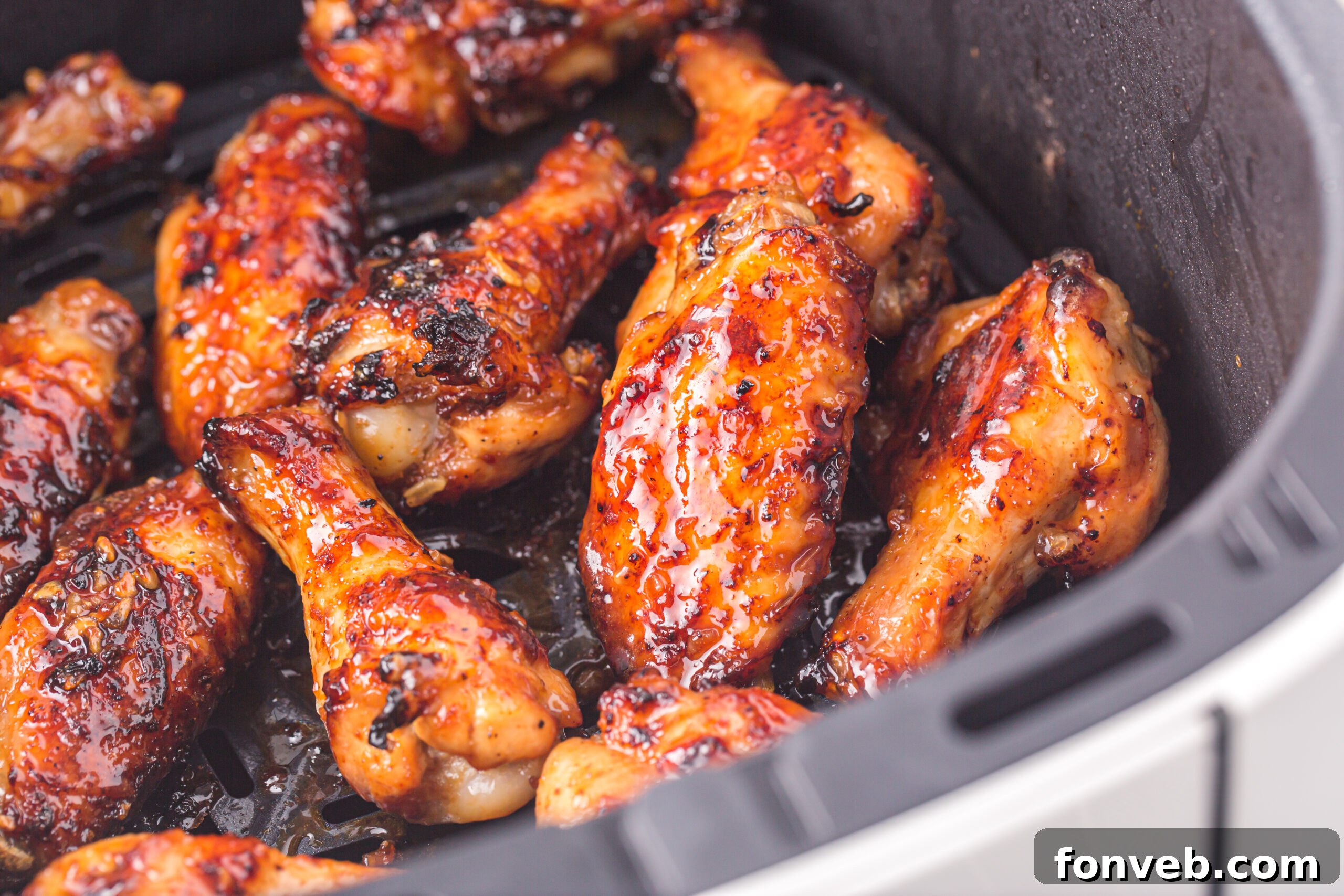 an Air Fryer Basket with the cooked Air Fryer Honey Garlic Chicken Wings inside