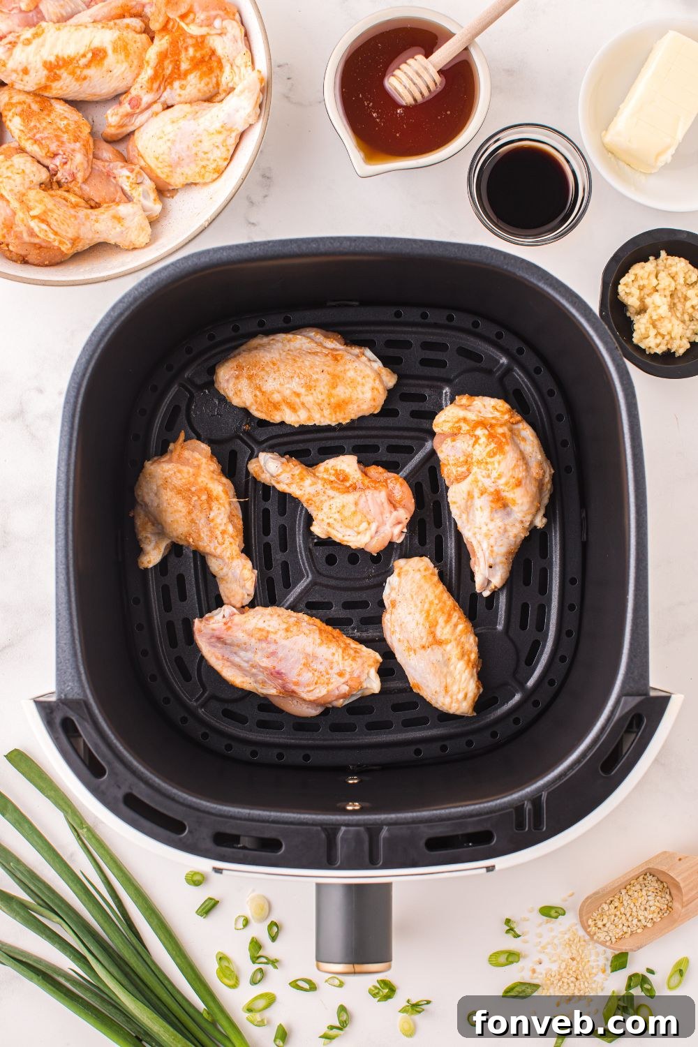 air fryer with chicken wings in an air fryer and sauce ingredients
