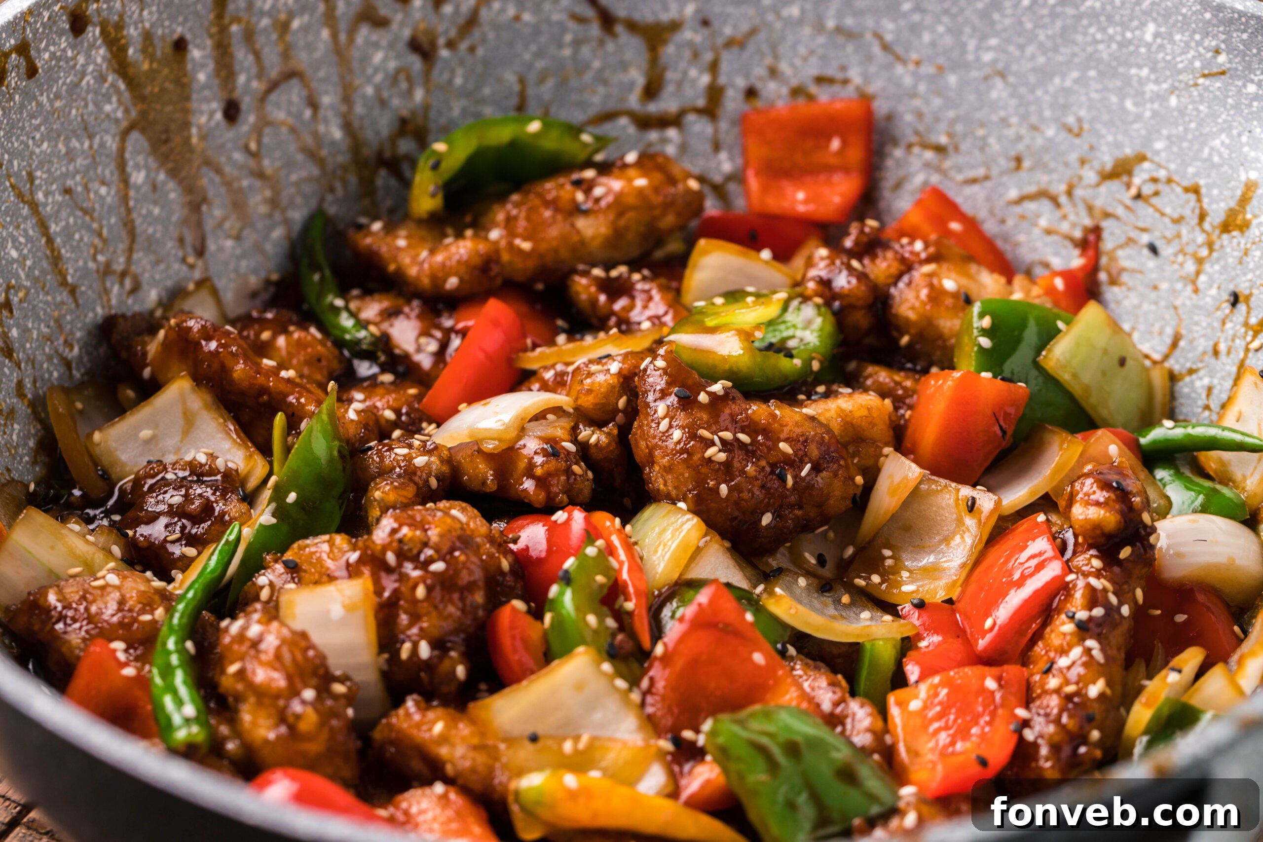 Side view of General Tso Chicken in a skillet, thoroughly covered in its rich, glossy sauce.